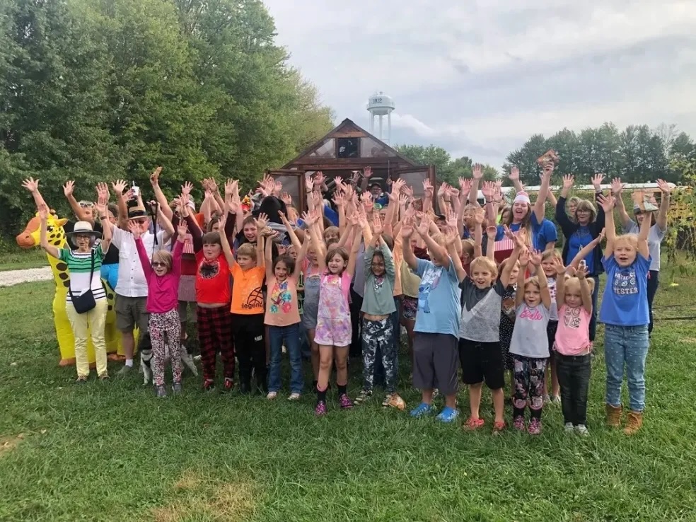 The Canaan Community Academy school community celebrating outside with hands raised